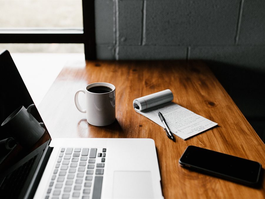 Office desk with laptop, notes, and coffee for support staff